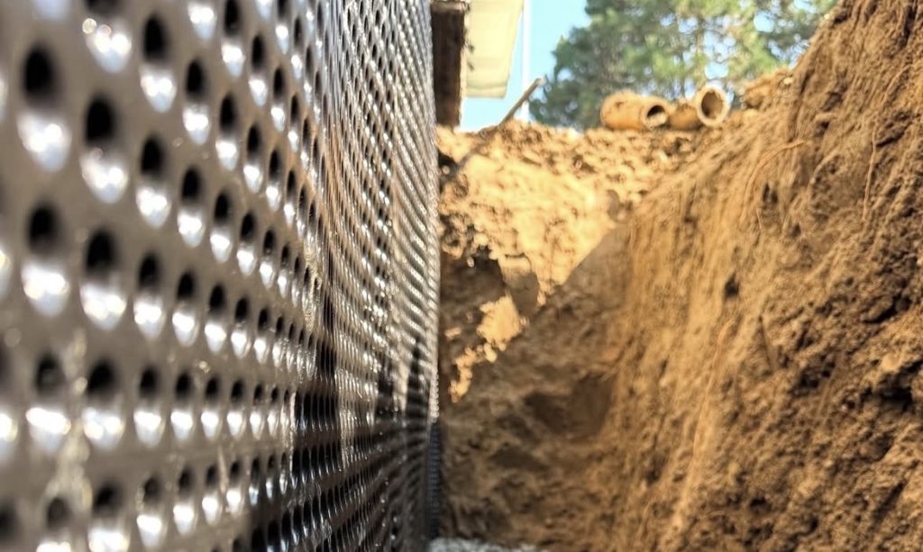 Exterior foundation waterproofing excavation and drain tile installation around basement foundation